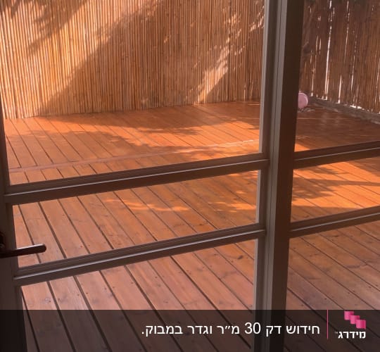 דק עץ עם גדר במבוק ועצים ברקע